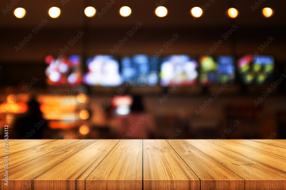Empty wooden table top with blurred coffee shop or restaurant interior background. Abstract background