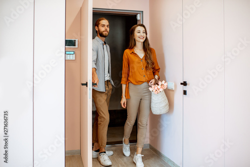 Beautiful young couple coming home, walking together in the pink corridor of the modern apartment