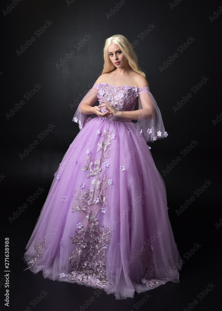 full length portrait of a blonde girl wearing a fantasy fairy inspired costume, long purple ball gown with fairy wings, standing pose on a dark studio background. full length portrait of a blonde girl wearing a fantasy fairy inspired costume, long purple ball gown with fairy wings, standing pose on a dark studio background.