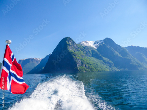 Photography Norwegian flag hanging on  the railing of the ship and waving above the water