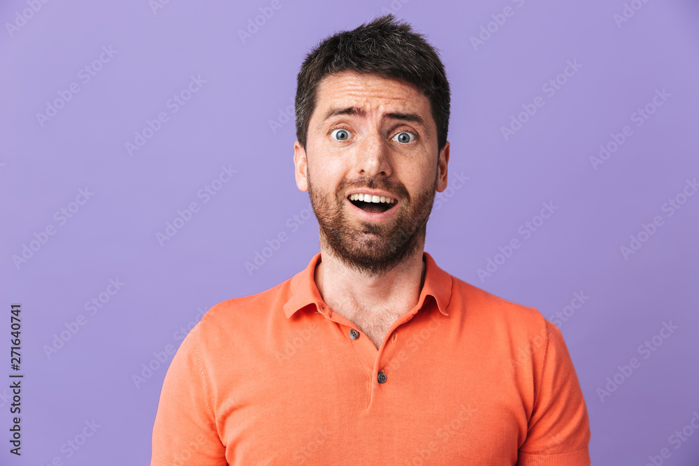 Obraz premium Excited shocked emotional young handsome bearded man posing isolated over violet purple wall background.