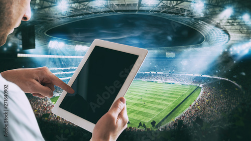 Photography Man with tablet at the stadium to bet on the game