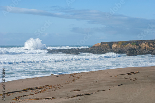 seascape of the central california coast at the monterey bay national marine sanctuary showing surf and sand under a partly cloudy sky