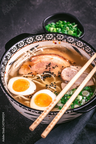 Udon Noodles in Japanese Ramen Soup with Pork, Eggs and Scallion on Dark Background
