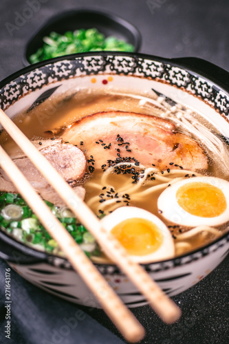 Udon Noodles in Japanese Ramen Soup with Pork, Eggs and Scallion on Dark Background