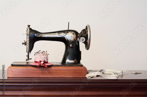 Old vintage sewing machine with measuring tape and pin cushion in shape of a hat