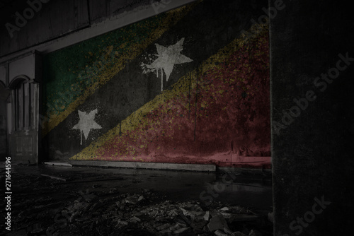 painted flag of saint kitts and nevis on the dirty old wall in an abandoned ruined house.