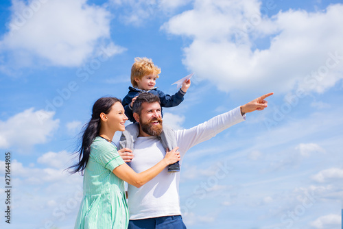 Daddy, mommy and child son. Happy family - child son playing with paper airplane. Portrait of happy father giving son piggyback ride on his shoulders, hug wife and looking up.