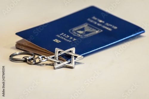 A blue passport of the State of Israel with a Star of David key chain by it. Israel citizenship concept, Israeli biometric "darkon" passport illustrative image. Jewish nation state concept.