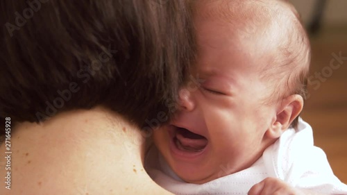 babyhood, motherhood and people concept - mother holding and soothing crying baby girl