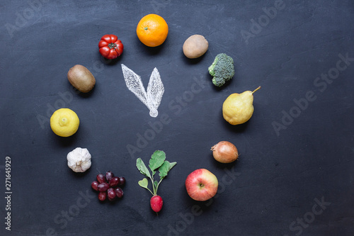 Fruits and vegetables building clock on dark ground with photo