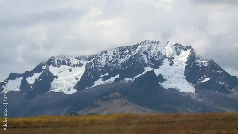 Medium close-up low-angle still shot of thick snow-white glacier flowing down slope from dark andean mountain peaks, Andes Peru Medium close-up low-angle still shot of thick snow-white glacier flowing down slope from dark andean mountain peaks, Andes Peru