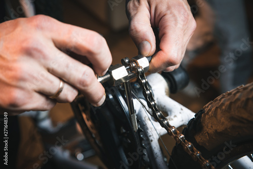 Bike service: mechanic serviceman repairman installing assembling or adjusting bicycle gear on wheel in workshop