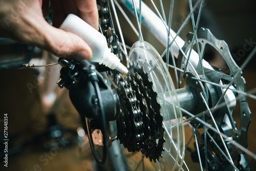 Closeup of male hands cleaning and oiling a bicycle chain and gear with oil spray. Working process