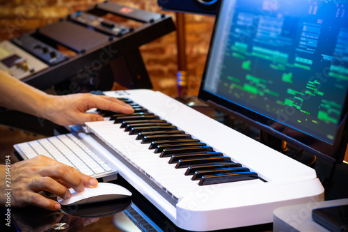 male professional music producer hands arranging a song on midi keyboard and computer in home studio. music production concept