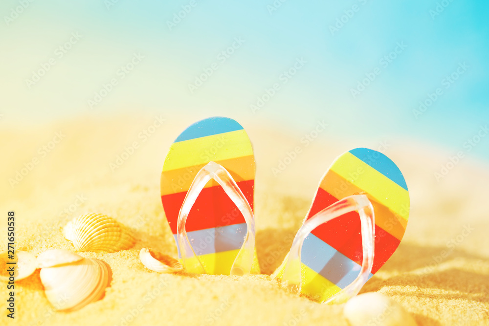 Vacation background with bright flip flops on sand against the sea, soft focus