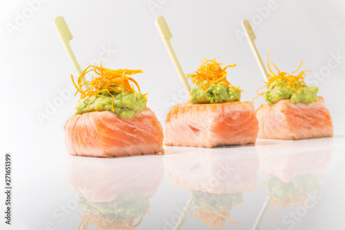 studio shot of healthy canape with salmon and guacamole in white background with its reflection