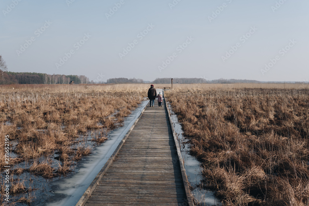 two people walking on a wooden path