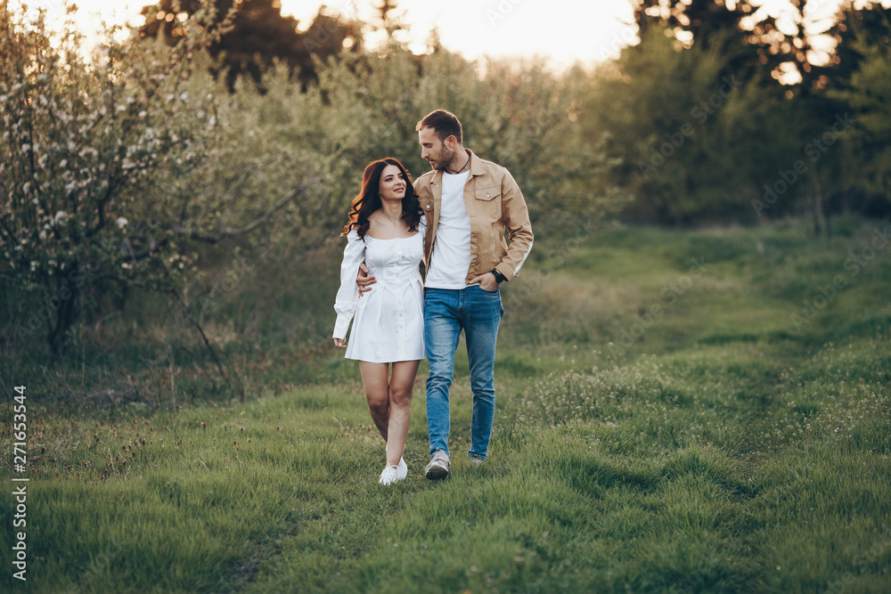 Young man and girl walking in the park at a sunset. A couple in love and happy at nature. Young man and girl walking in the park at a sunset. A couple in love and happy at nature.