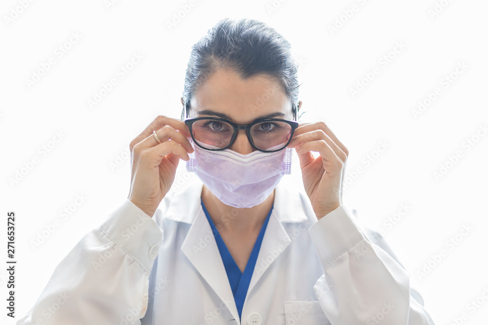 Young attractive female stomatologist with ring in medical gown, mask and glasses looking at camera isolated on white background Young attractive female stomatologist with ring in medical gown, mask and glasses looking at camera isolated on white background