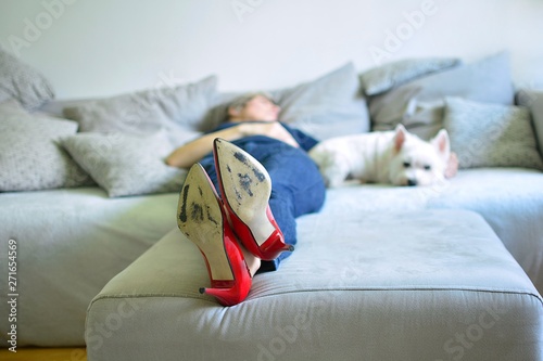 adult woman lying on sofa with white dog