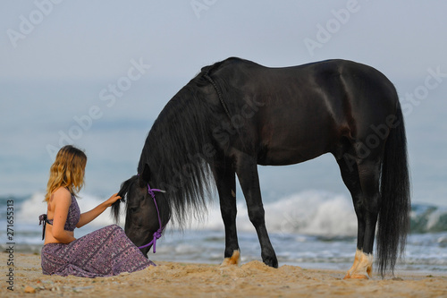Portrait of a beautiful blond girl run on the sand with her black horse on the Rishpon beach, Israelck horse on the Rishpon beach, Israel