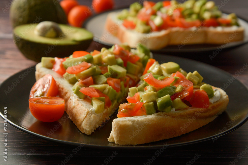 Healthy toast with avocado, cherry tomatoes and cheese on a plate. Wooden table.