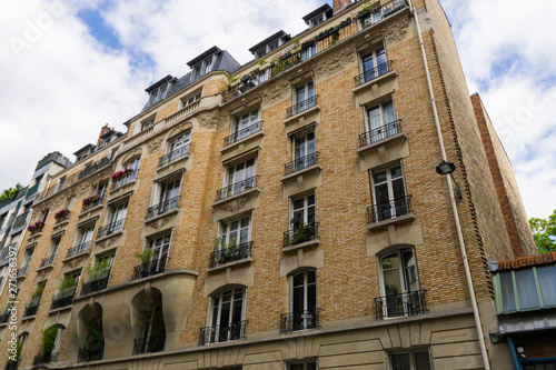 Building with large windows and balconies with flowers in Paris against a cloudy sky