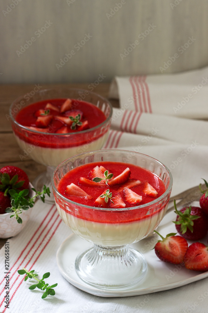 Panna cotta with strawberry sauce and strawberry slices, decorated with thyme leaves. Rustic style.