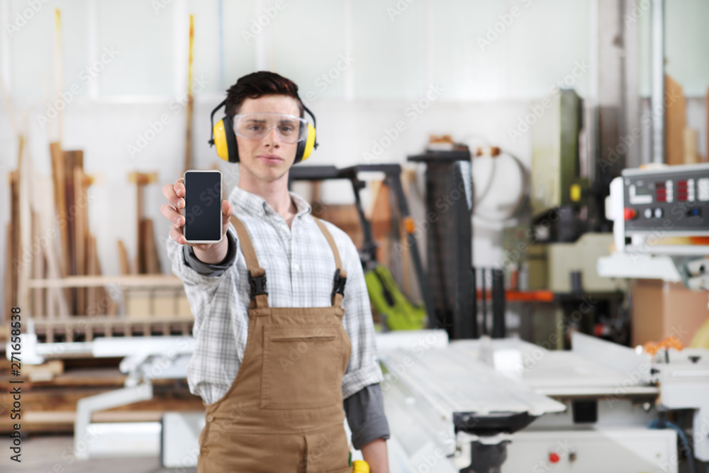 carpenter man show the mobile phone isolated on carpentry background carpenter man show the mobile phone isolated on carpentry background