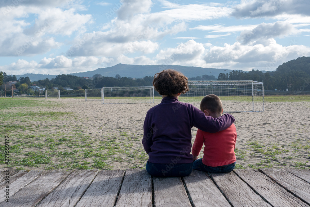 Boy and girl hugging and sitting next to some football goals
