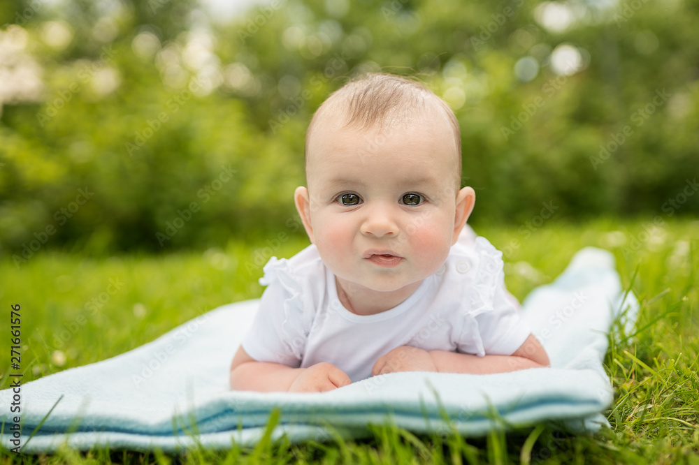 cute girl laying on a grass looking directly into the camera 