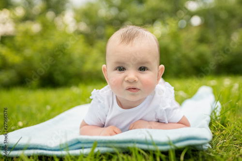 cute girl laying on a grass looking directly into the camera  © Lumistudio