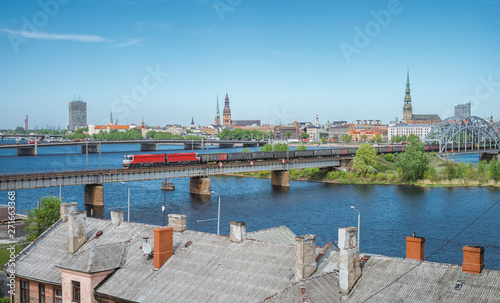 Panoramic view of Riga city covered in clouds. Iconic railroad bridge and old town panorama across the river  Daugava. Picturesque scenery of historical architecture. National library of Latvia.