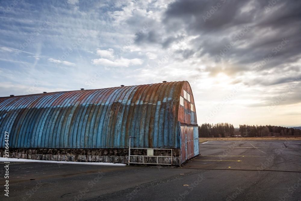 aircraft hangar with the sun and an upcoming storm in the background