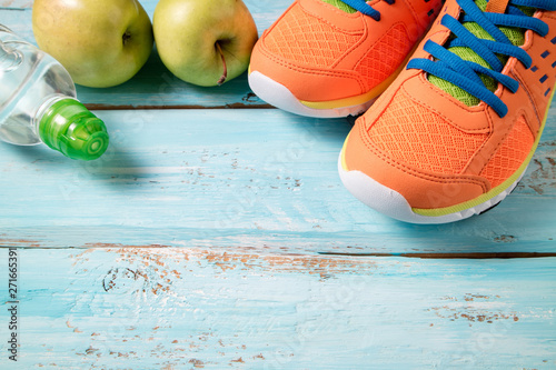 Sport shoes  apples  bottle of water on blue wooden background. Concept healthy lifestyle  healthy food  sport and dieting. Sport equipment