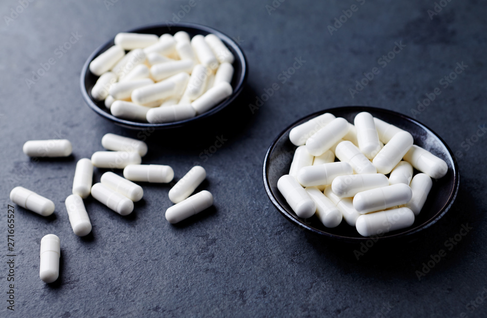 Arginine alpha-ketoglutarate (AAKG) and Creatine capsules. Bodybuilding food supplements on dark stone background. Copy space. Arginine alpha-ketoglutarate (AAKG) and Creatine capsules. Bodybuilding food supplements on dark stone background. Copy space.