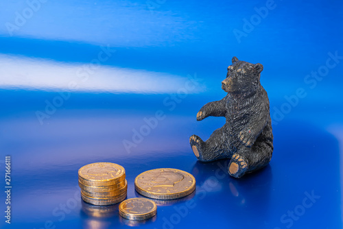 Bear with gold coins on a blue background to illustrate a Bear Market.