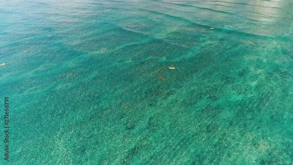 Flying over open water, focusing on a single person on a yellow paddle board. Flying over open water, focusing on a single person on a yellow paddle board.