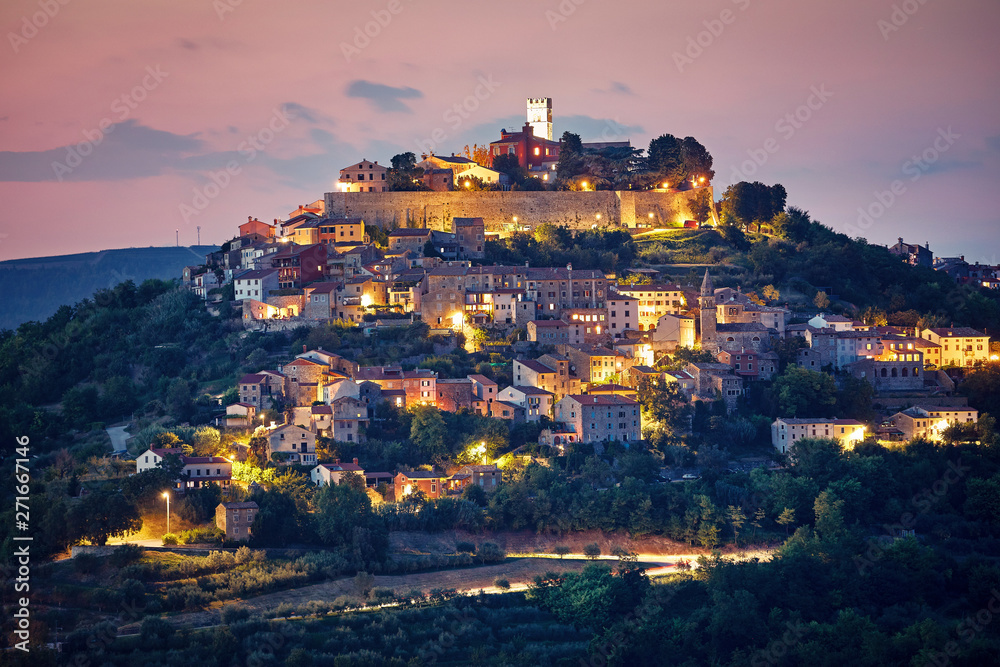 Croatia. Vintage Motovun walled city fortress on the hill. Picturesque evening sunset landscape. Summer panorama. Backlighting illumination at houses and walls.
