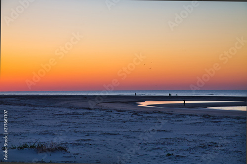 Fotografie People Walking on the Beach in the Predawn Light