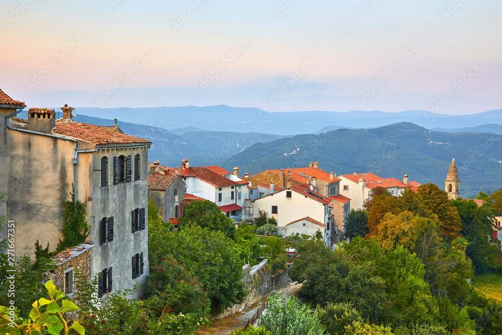 Motovun, Croatia. Ancient town at knoll with houses with red tegular roofs. Picturesque evening sunset. Panorama view.
