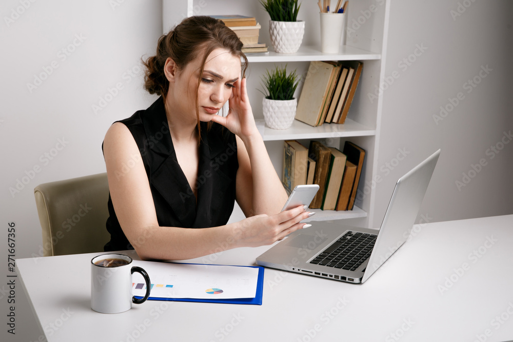 Confused and serious office woman working phone sitting at her desk Confused and serious office woman working phone sitting at her desk