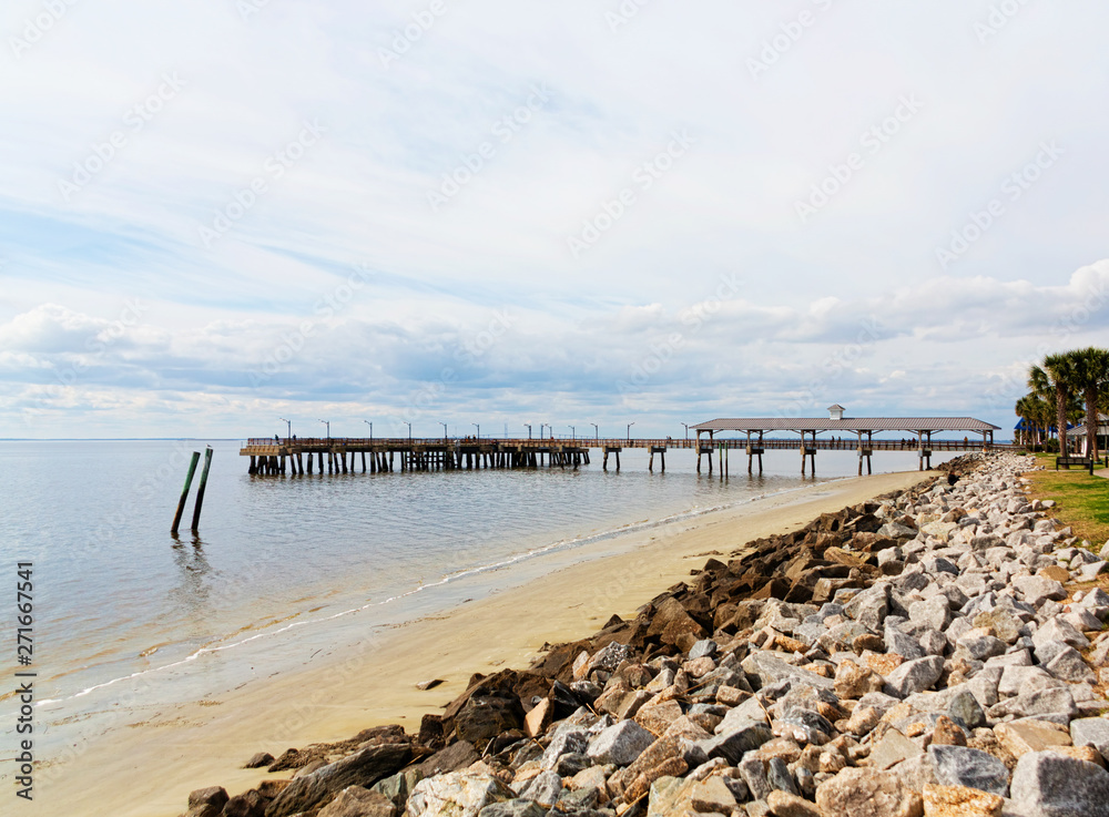 An old fishing pier on St Simons Island beyond rock seawall An old fishing pier on St Simons Island beyond rock seawall