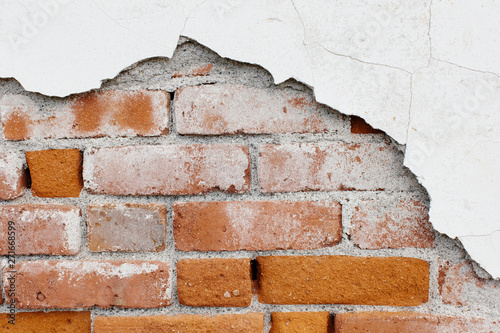 A brick wall and plasterwork flaking off. ,Peeling paint and exposed old brick wall photo