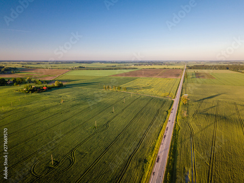Aerial view of empty road during sunrise surrounded by agricultural fields
