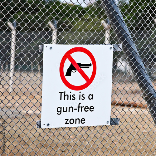 A Gun-free zone signpost on a fence. Gun control in America concept image. 