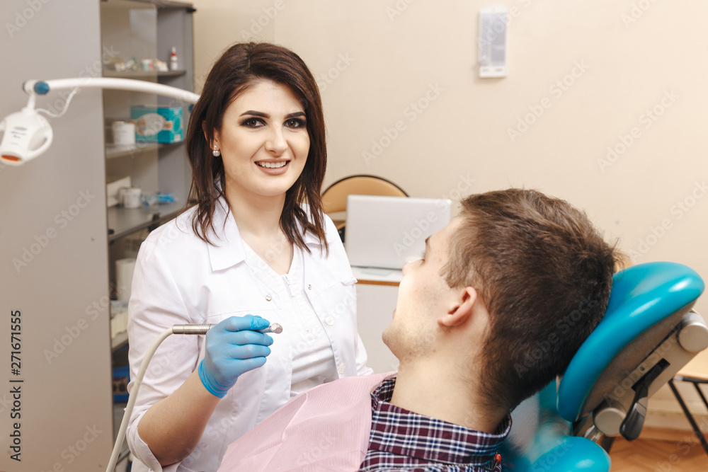 Picture of young female dentist in white coat working with male patient in the dental room Picture of young female dentist in white coat working with male patient in the dental room