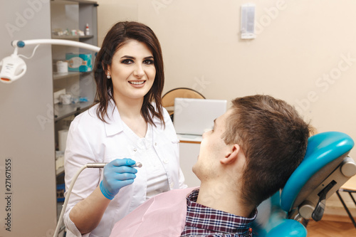 Picture of young female dentist in white coat working with male patient in the dental room