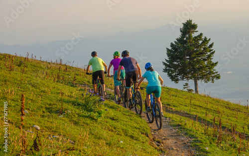 Group of mountain bikers pedalling their electric bikes up a narrow dirt road.